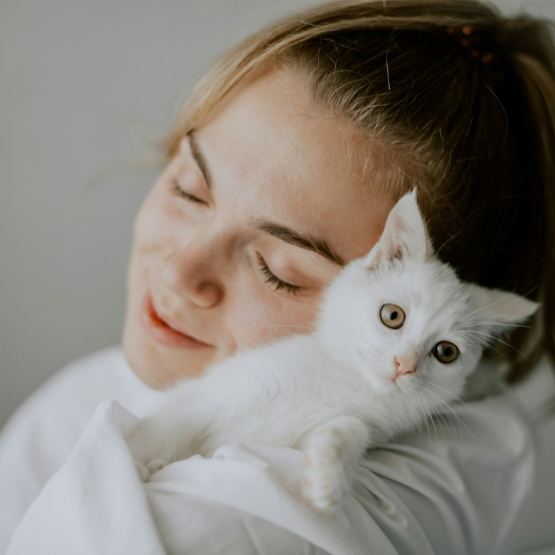 woman embraces white kitten